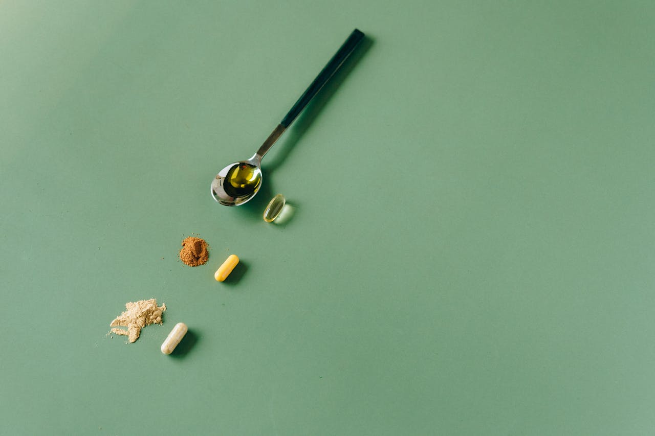 Assorted herbal supplements and powders on a green backdrop with a spoon.